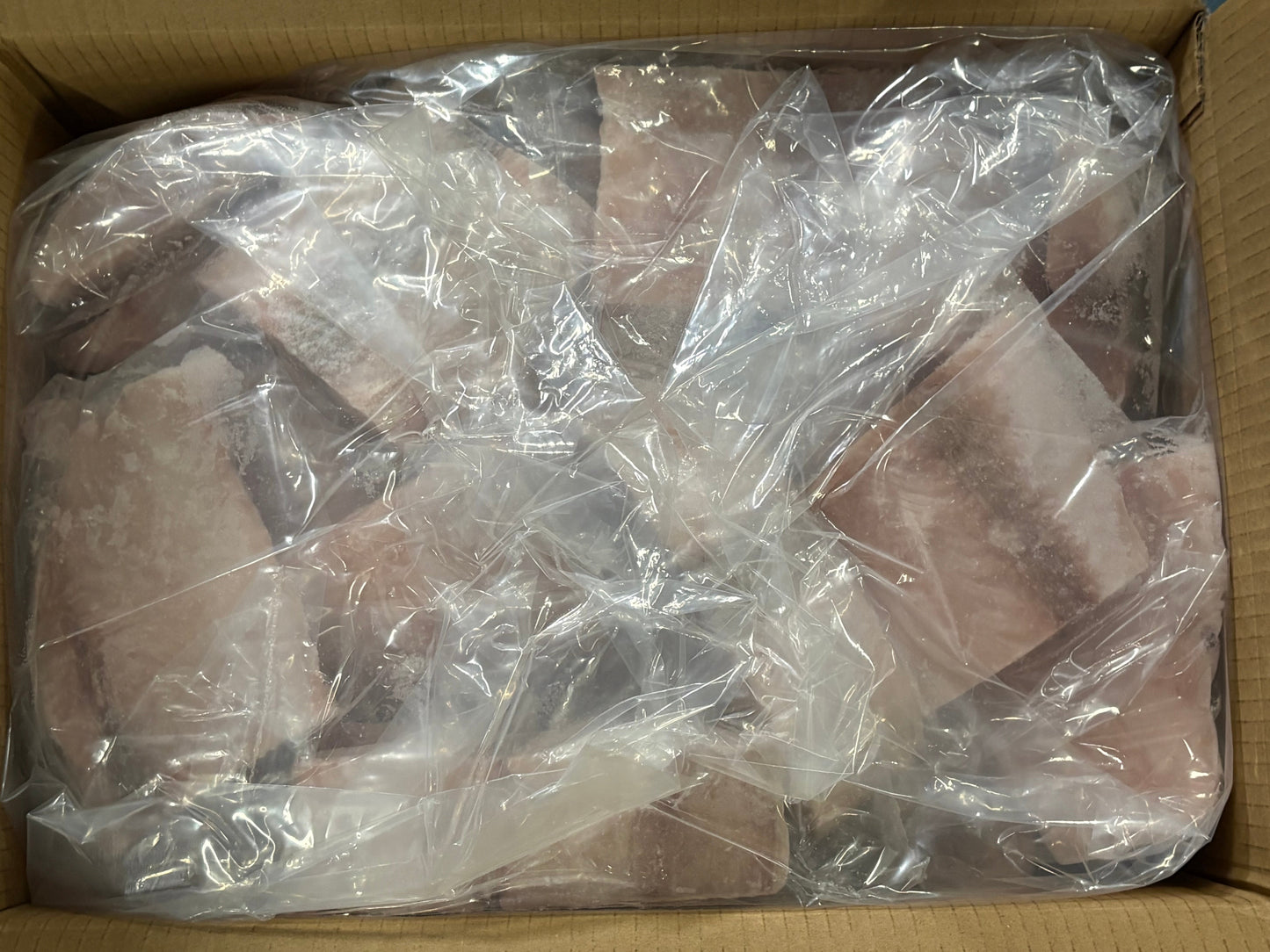 Frozen mahi mahi fillets wrapped in clear plastic bags, packed inside a cardboard box.